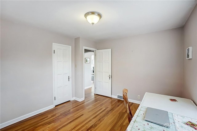 office area featuring visible vents, light wood-style floors, baseboards, and arched walkways