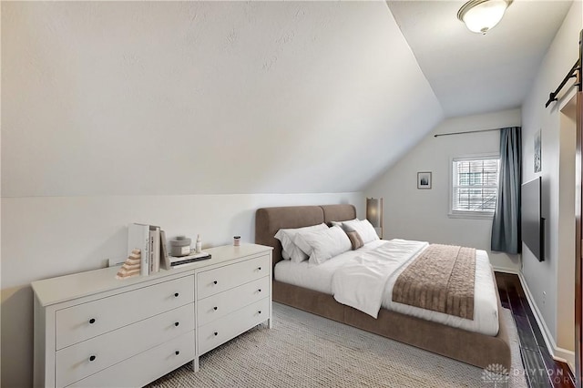 bedroom with wood finished floors, baseboards, and vaulted ceiling