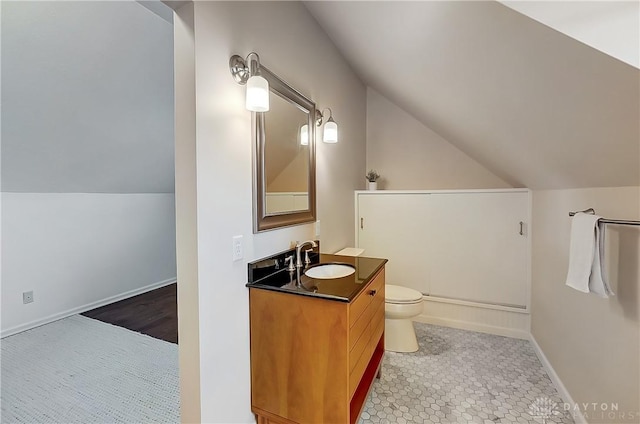 bathroom with vanity, vaulted ceiling, toilet, and baseboards