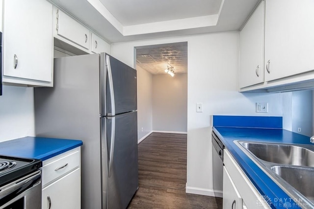 kitchen with a sink, dark wood finished floors, appliances with stainless steel finishes, white cabinets, and baseboards