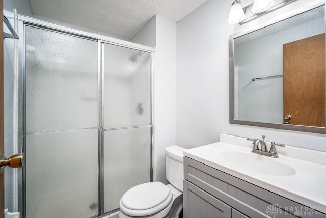 bathroom featuring a shower stall, a textured ceiling, toilet, and vanity