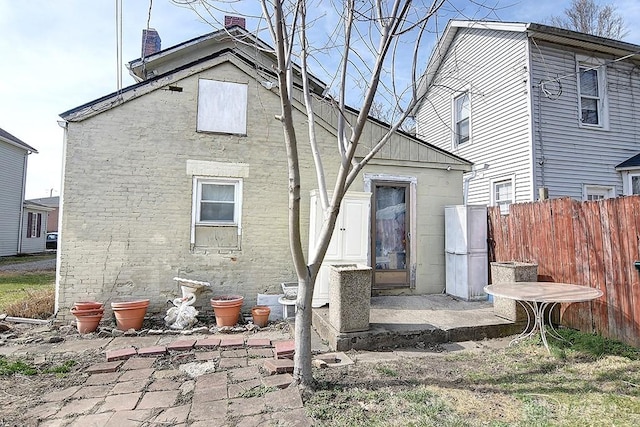 rear view of property featuring a patio area, a chimney, and fence