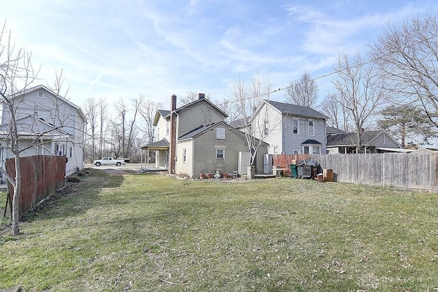 rear view of property featuring a yard, a residential view, and fence