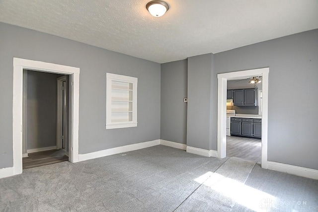 unfurnished room with built in features, light colored carpet, baseboards, and a textured ceiling