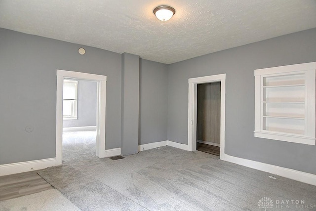 unfurnished room with baseboards, carpet floors, and a textured ceiling