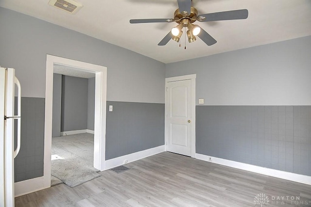 empty room featuring visible vents, baseboards, ceiling fan, and wood finished floors