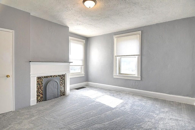 unfurnished living room with baseboards, visible vents, carpet floors, a fireplace, and a textured ceiling