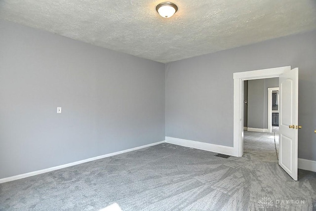 carpeted empty room with baseboards and a textured ceiling