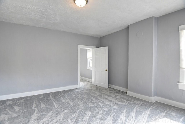 carpeted spare room featuring baseboards and a textured ceiling