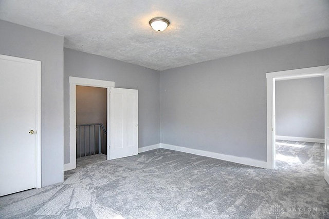 unfurnished bedroom featuring a textured ceiling, baseboards, and carpet floors