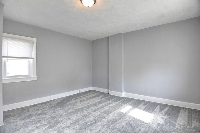 carpeted empty room featuring baseboards and a textured ceiling