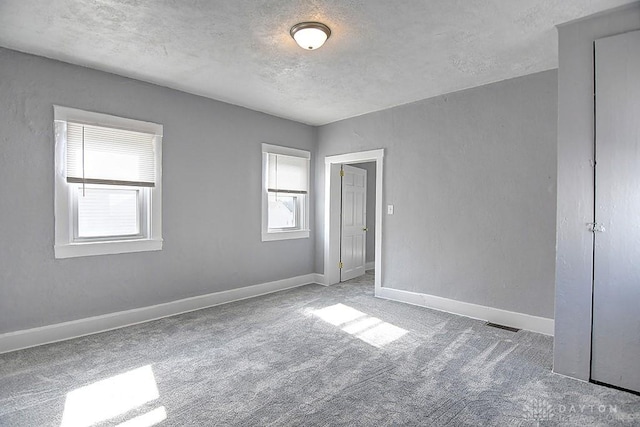 unfurnished bedroom with a textured ceiling, baseboards, and carpet floors