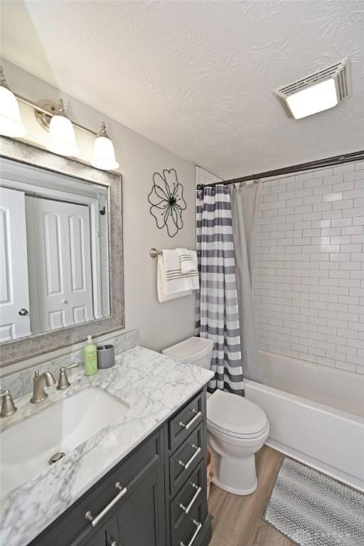 bathroom featuring vanity, wood finished floors, visible vents, a textured ceiling, and toilet