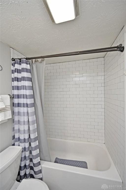 full bathroom with shower / tub combo, toilet, and a textured ceiling