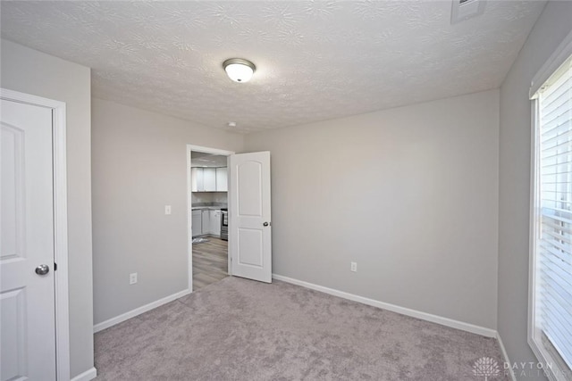 unfurnished bedroom featuring visible vents, a textured ceiling, baseboards, and carpet floors