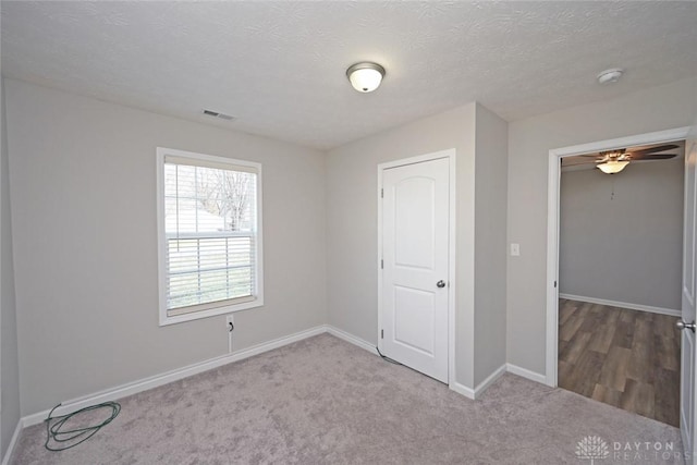 unfurnished bedroom with visible vents, carpet floors, a textured ceiling, and baseboards