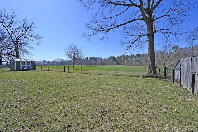 view of yard featuring a rural view, a storage unit, an outbuilding, and fence