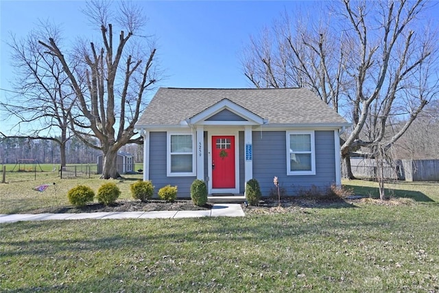 bungalow-style house with a front yard, roof with shingles, and fence