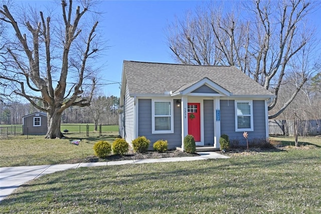 bungalow with fence, a front yard, and a shingled roof