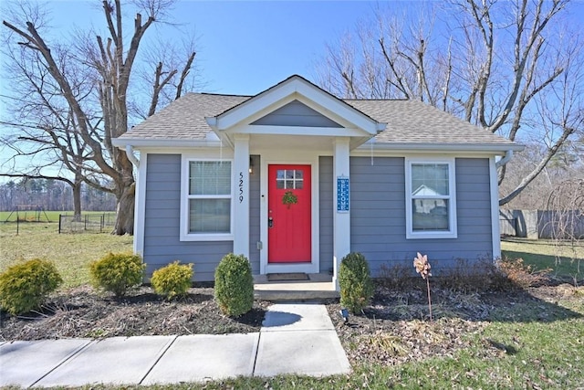 bungalow-style home featuring roof with shingles and fence