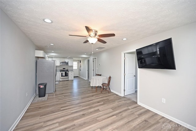 unfurnished living room featuring baseboards, recessed lighting, light wood-style floors, a textured ceiling, and a ceiling fan