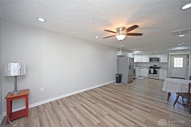 living room with light wood-style flooring, baseboards, visible vents, and ceiling fan