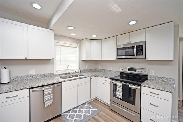 kitchen featuring a sink, light wood-type flooring, appliances with stainless steel finishes, and white cabinetry