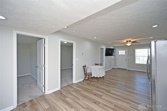 interior space with light wood-type flooring, baseboards, and a textured ceiling