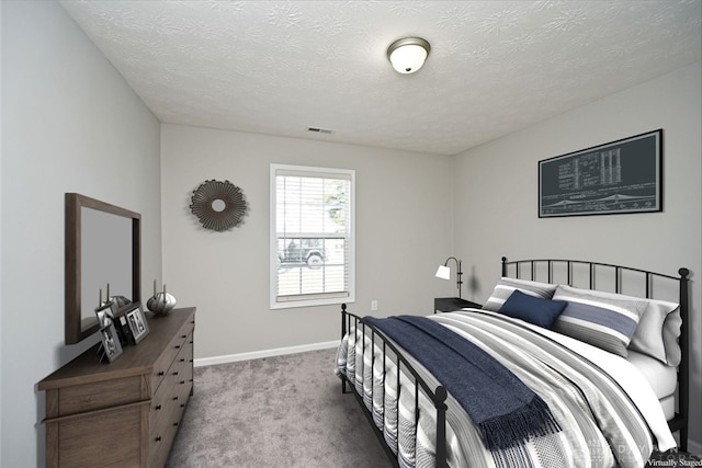 bedroom with visible vents, carpet floors, a textured ceiling, and baseboards