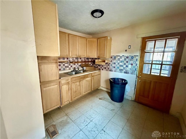 kitchen with light countertops, light brown cabinets, visible vents, and a sink