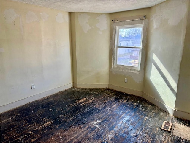 unfurnished room with visible vents, baseboards, a textured ceiling, and hardwood / wood-style flooring