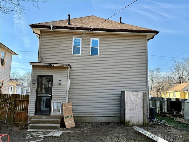 back of property with roof with shingles and fence