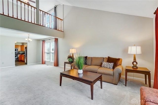 living area with a notable chandelier, light colored carpet, baseboards, and high vaulted ceiling