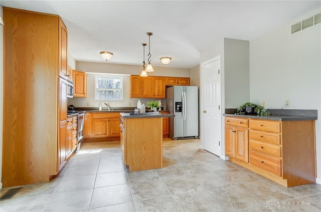 kitchen with dark countertops, a kitchen island, stainless steel appliances, and visible vents