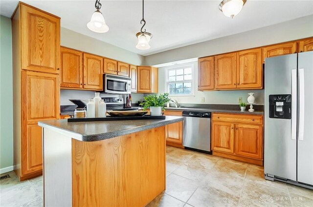 kitchen with dark countertops, hanging light fixtures, appliances with stainless steel finishes, and a kitchen island