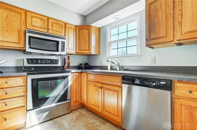 kitchen with a sink, stainless steel appliances, and dark countertops