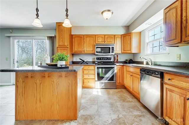 kitchen with a kitchen island, a sink, appliances with stainless steel finishes, dark countertops, and decorative light fixtures