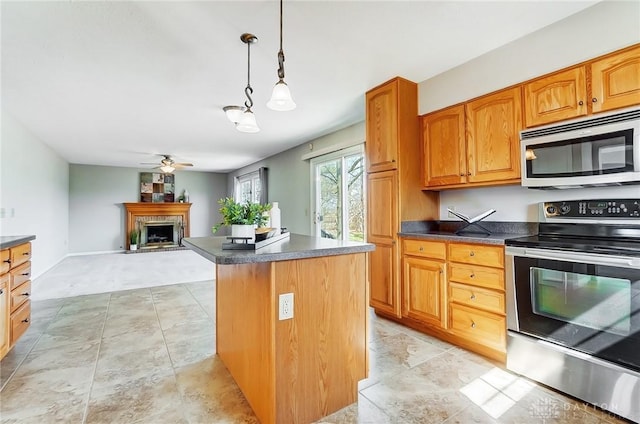 kitchen with a ceiling fan, dark countertops, a center island, stainless steel appliances, and hanging light fixtures