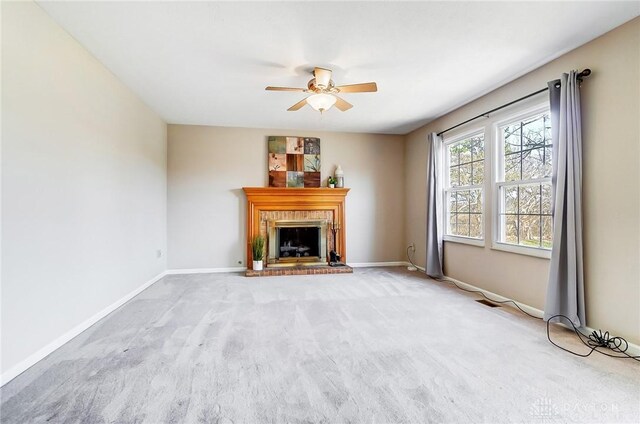 unfurnished living room featuring a fireplace, carpet, baseboards, and ceiling fan