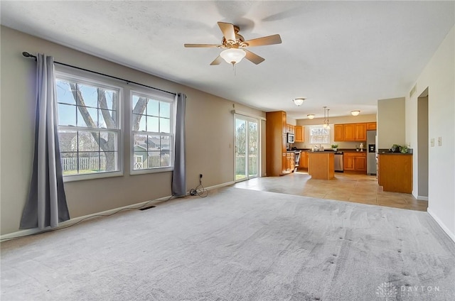 unfurnished living room with visible vents, baseboards, light carpet, light tile patterned floors, and a ceiling fan