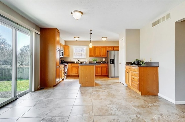 kitchen with visible vents, a kitchen island, dark countertops, stainless steel appliances, and baseboards