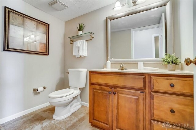 bathroom featuring visible vents, baseboards, toilet, and vanity