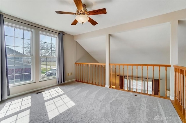 carpeted spare room with visible vents, baseboards, ceiling fan, and vaulted ceiling