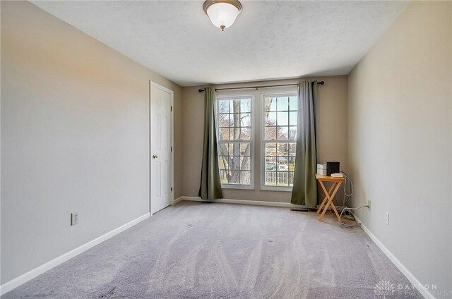 unfurnished room with baseboards, carpet floors, and a textured ceiling