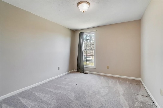 spare room with baseboards and carpet floors