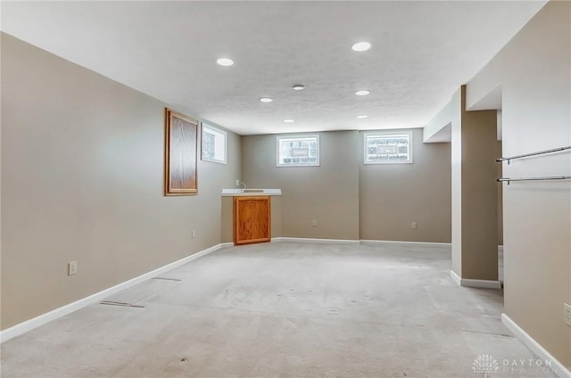 basement featuring recessed lighting, light colored carpet, baseboards, and a textured ceiling