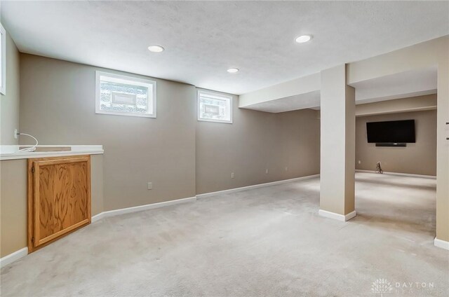 basement with recessed lighting, baseboards, light colored carpet, and a sink