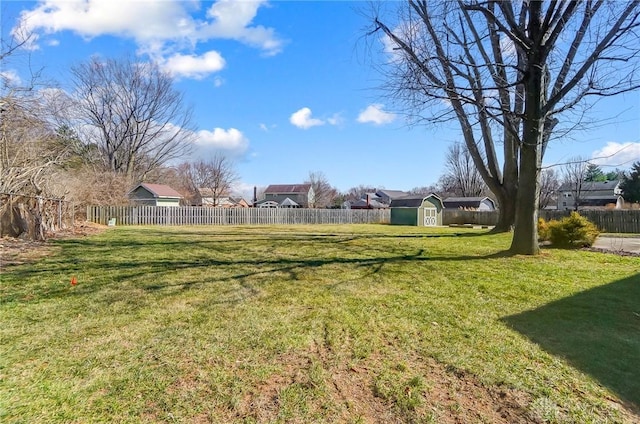 view of yard featuring a storage shed, a fenced backyard, and an outbuilding