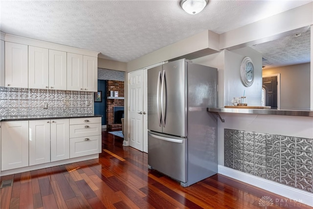 kitchen featuring dark wood-type flooring, white cabinets, dark countertops, and freestanding refrigerator