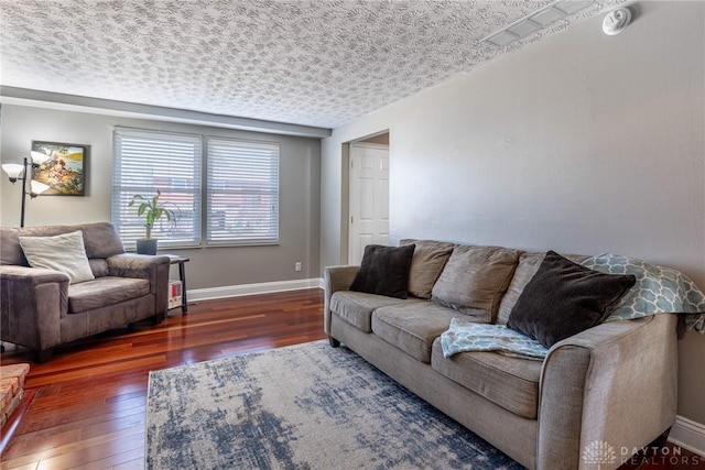 living room with hardwood / wood-style flooring, baseboards, and a textured ceiling